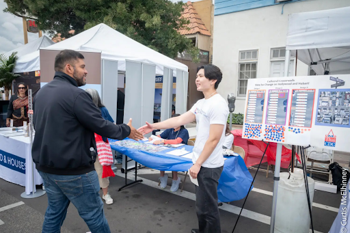 Steven Tran greets L.A. City Councilman Hugo Soto-Martinez at the Songkrean Festival in Thai Town. (photo: Curtis McElhinney) ALT TEXT: Talking with Council District 13 Member Hugo Soto Martinez about our CPIO and the importance of having a cultural crosswalk in Thai Town.